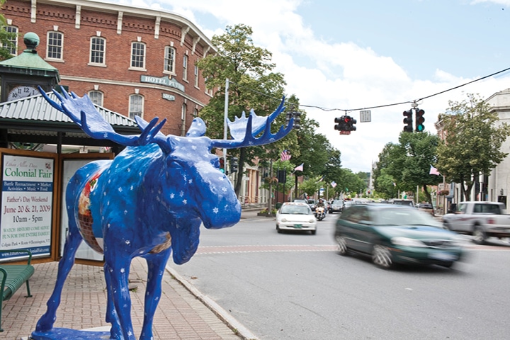 Downtown street with blue moose statue in foreground