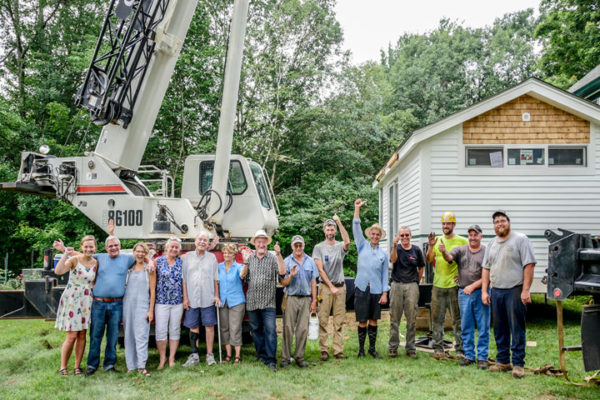Group of people posed in front of a new house and a crane Wheel Pad