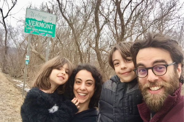 A family of four standing in front of the Welcome to Vermont sign