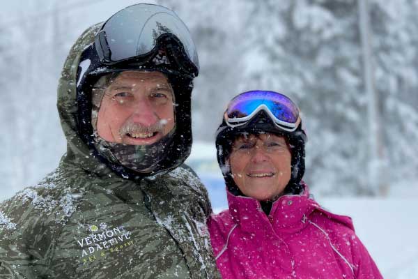 A man and a woman wearing ski helmet and goggles