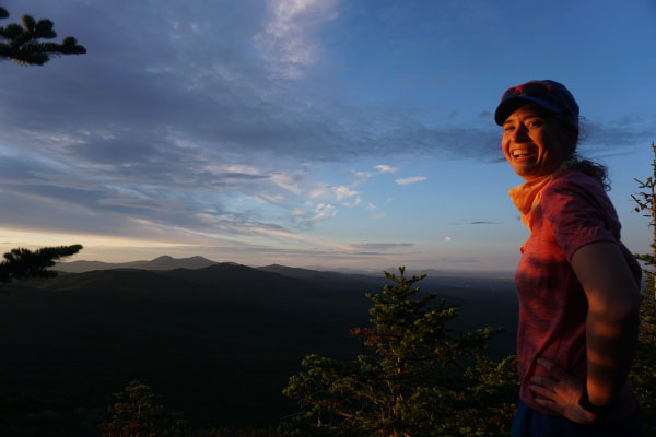 A woman standing on a mountain at sunset