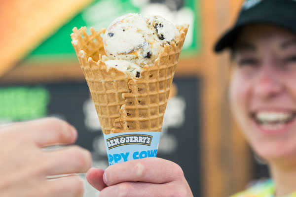 woman hands a customer a Ben and Jerry's ice cream cone