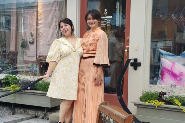 Two women stand in front of a storefront