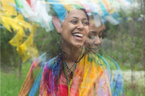 A woman dressed in rainbow clothing smiles