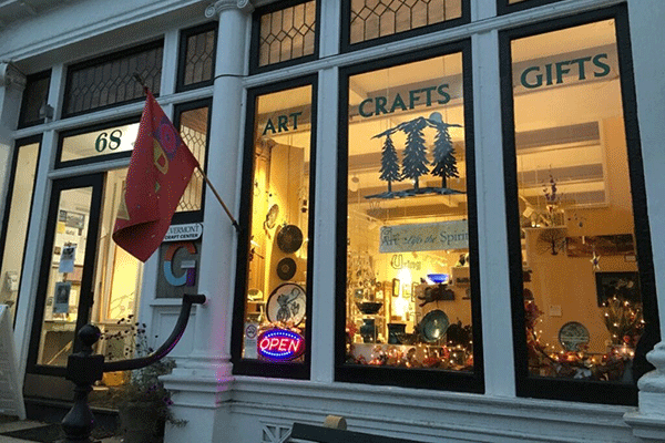 A grey stone building with wide windows featuring the words “Art,” “Craft,” and “Gifts.”