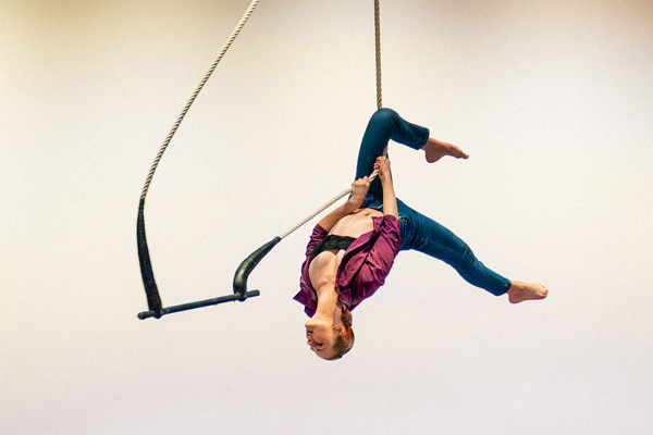 A trapeze artist suspended in the air. 