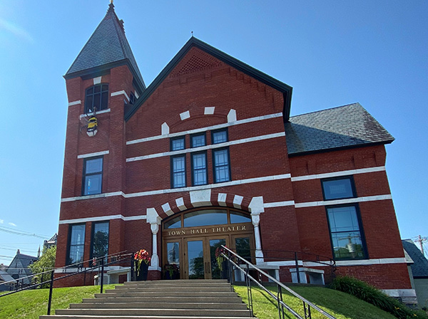  A historic building with a sign reading “Town Hall Theatre” seen from outside on a sunny day. 