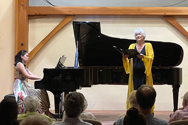 A person plays piano while another person sings on a stage. 