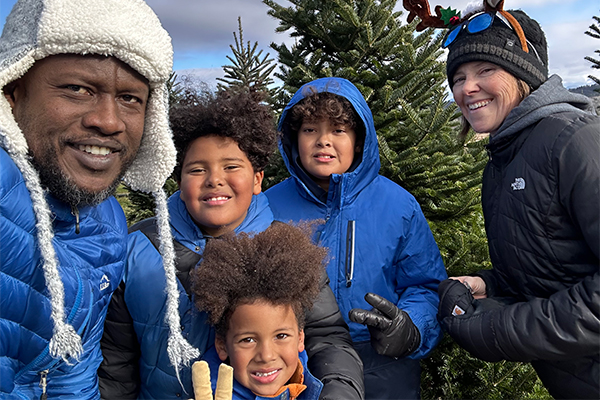 A family of five smiling at the camera outside in the winter. 